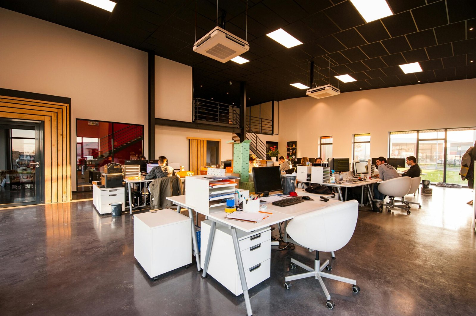 Profil A spacious and modern open-plan office with natural lighting and employees working at desks.